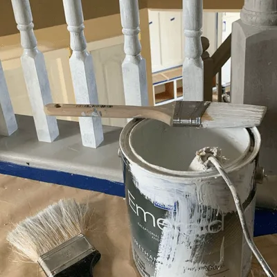 Paint can and brush during a stair railing repaint